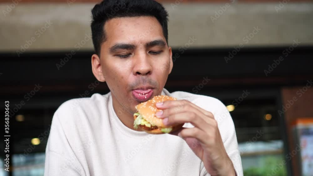 close up young man holding hamburger sandwich and eating in the after after feeling hungry for fast food and unhealthy lifestyle concept close up young man holding hamburger sandwich and eating in the after after feeling hungry for fast food and unhealthy lifestyle concept