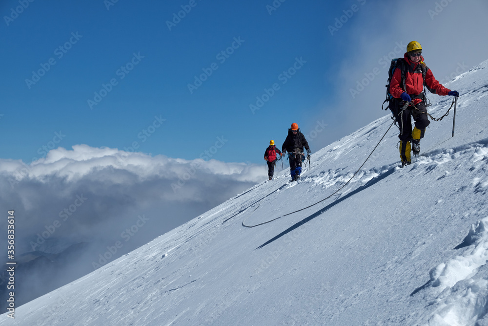 Bunch of mountaineers climbs or alpinists to the top of a snow-capped mountain