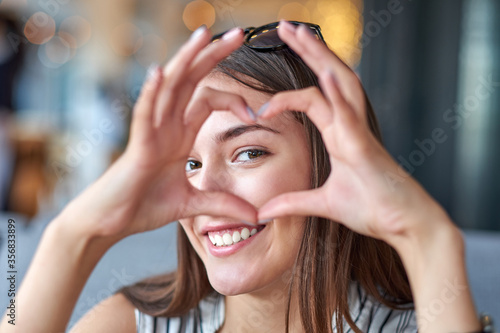 Beautiful woman looking through heart gesture made with hands