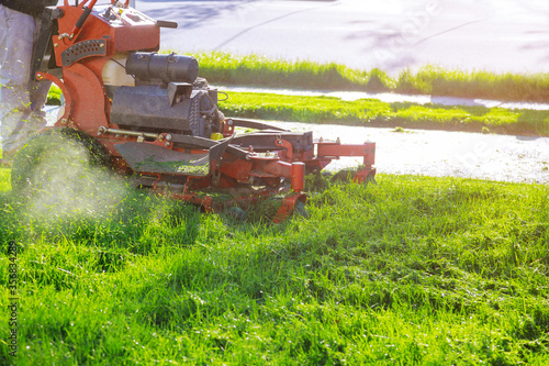 Man worker cutting grass in summer with a lawn mower