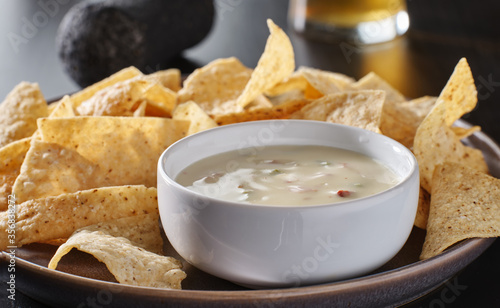 mexican hot queso blanco cheese dip with corn tortilla chips on plate
