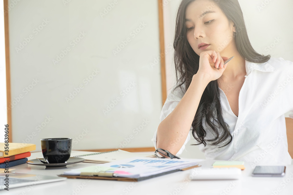 Young asian entrepreneur cogitating thinking making important decision at workplace. Concentrated serious office worker millennial woman analysing results