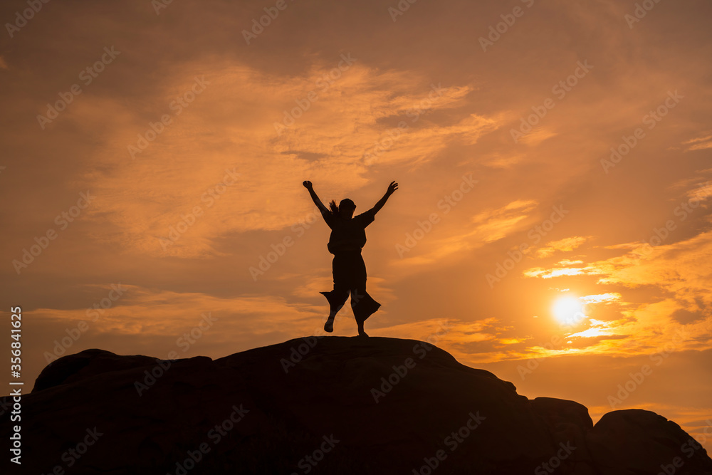 The silhouette of a woman successfully carrying herself to the top of a mountain hill