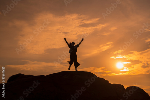 The silhouette of a woman successfully carrying herself to the top of a mountain hill