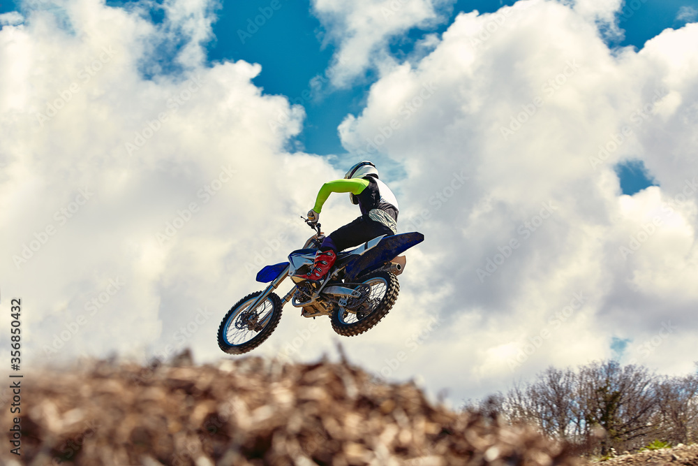 Extreme concept, challenge yourself. Extreme jump on a motorcycle on a background of blue sky with clouds. Copy space, all or nothing. Extreme concept, challenge yourself. Extreme jump on a motorcycle on a background of blue sky with clouds. Copy space, all or nothing.