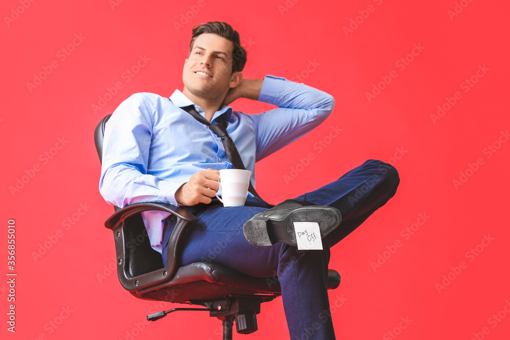 Young businessman relaxing on chair against color background. Day off concept Young businessman relaxing on chair against color background. Day off concept