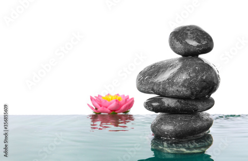 Spa stones and flower in water against white background