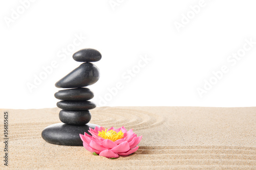 Stones and flower on sand against white background. Zen concept