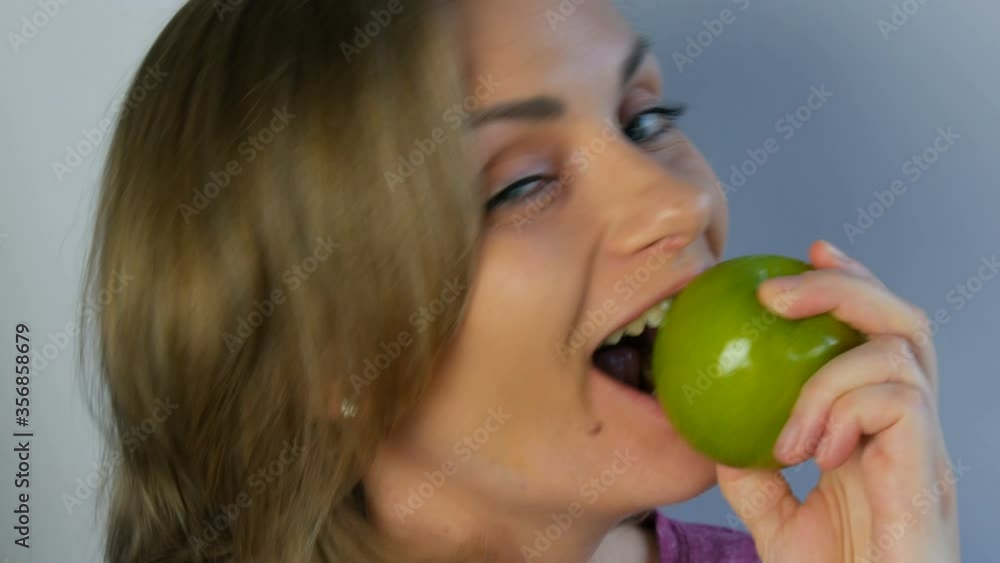 Face portrait of a young beautiful woman with an appetite and funny eating a big green apple, biting off pieces. Vegetarianism concept, fresh fruits in the hands of a young girl, healthy food. Face portrait of a young beautiful woman with an appetite and funny eating a big green apple, biting off pieces. Vegetarianism concept, fresh fruits in the hands of a young girl, healthy food.