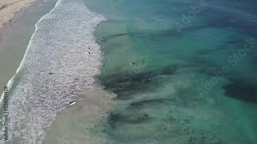 Aerial view above surfer riding waves on their boards at Indian Ocean coast of Western Australia, with turquoise water as background and copy space.