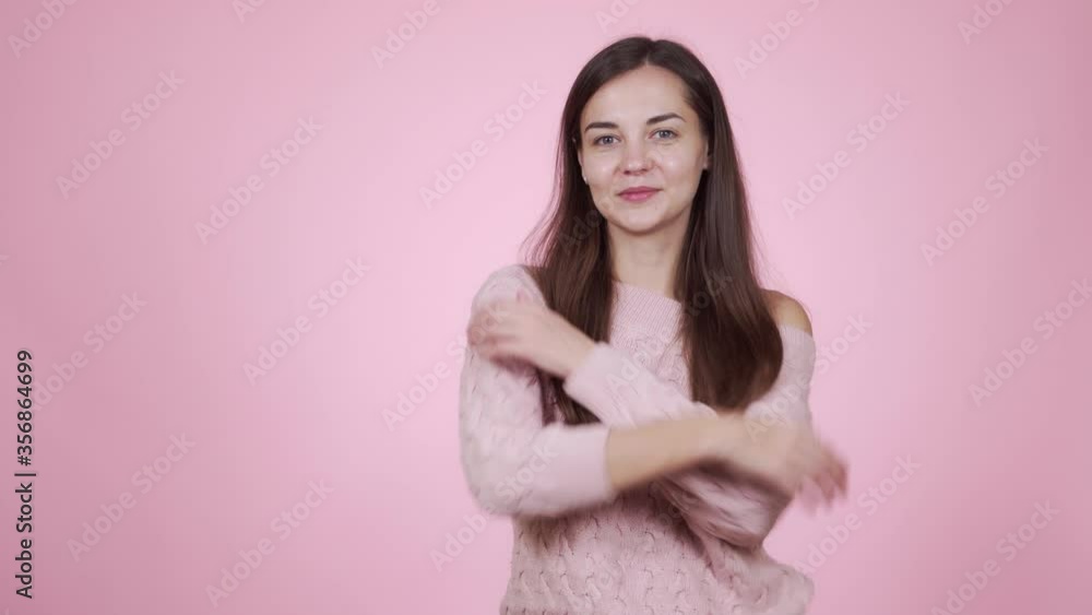 Woman in pink knitted sweater posing on camera isolated on pink background Woman in pink knitted sweater posing on camera isolated on pink background