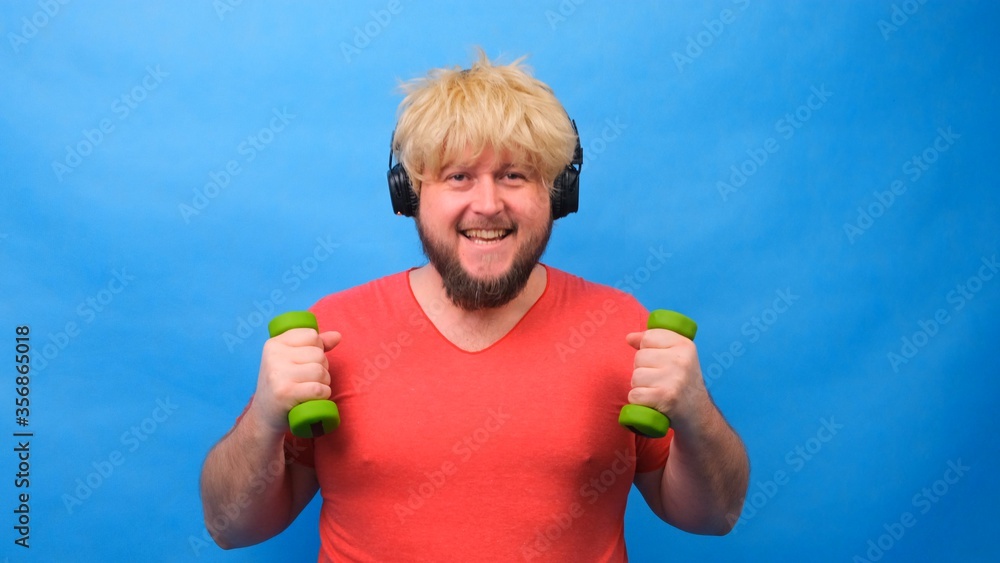 Funny fat man with dumbbells doing exercises on a blue background. Funny fat man with dumbbells doing exercises on a blue background.