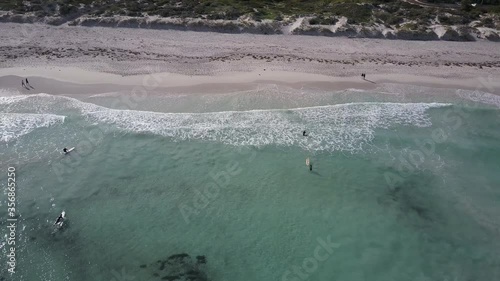 Aerial view above surfer riding waves on their boards at Indian Ocean coast of Western Australia, with turquoise water as background and copy space.