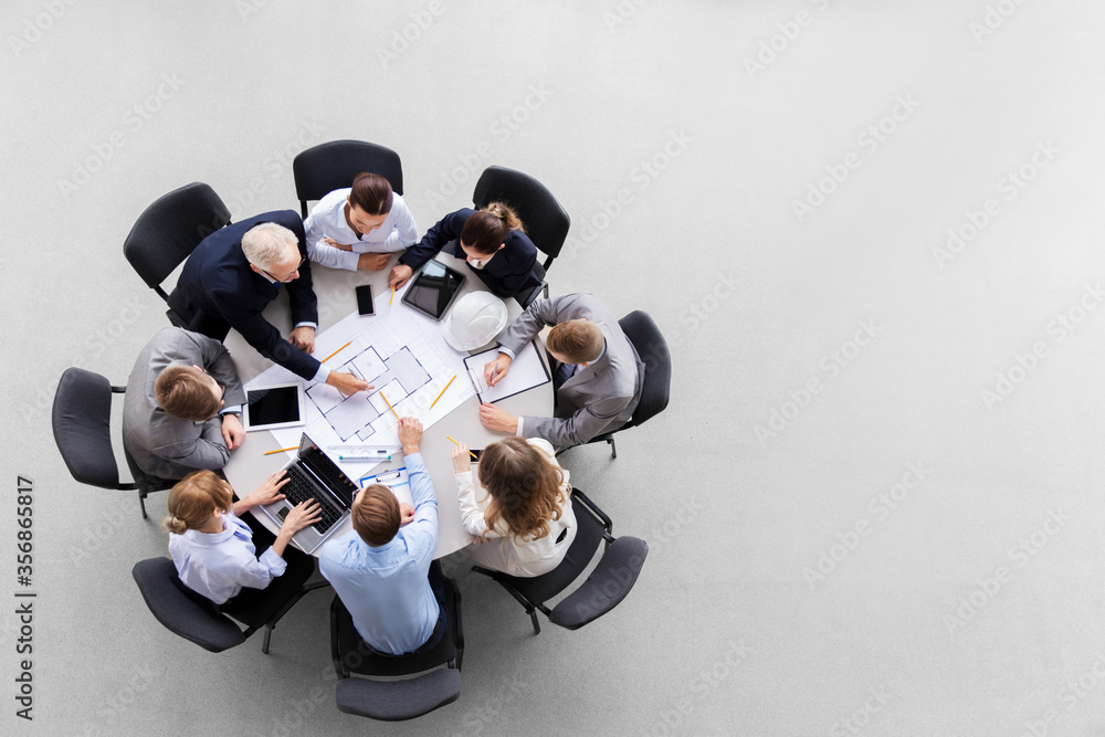 © Syda Productions - construction business, architecture and building concept - group of architects with laptop computer discussing blueprint at office