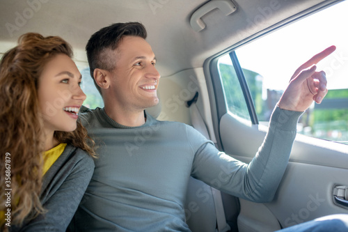 Young adult guy and girl sitting in backseat in car