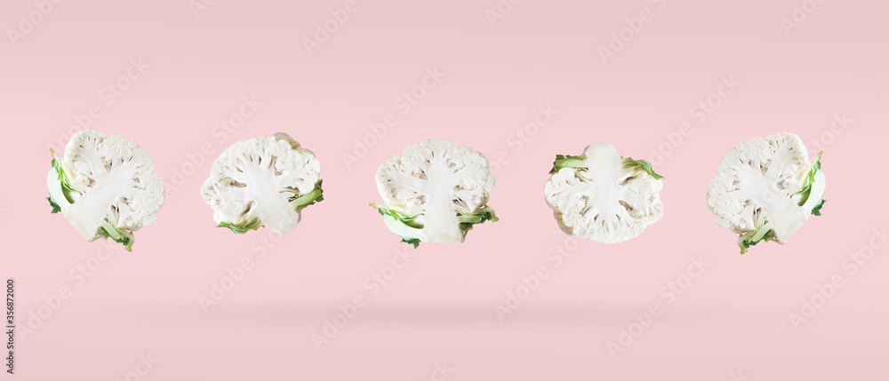Freshly cut in half cauliflower five pieces soaring on a pink background. Vegetables levitation concept, minimalistic grocery banner with copy space for text. Freshly cut in half cauliflower five pieces soaring on a pink background. Vegetables levitation concept, minimalistic grocery banner with copy space for text.