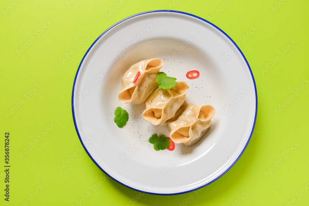 Flat lay fresh boiled dumplings with hot steams served on white plate. Asian food on bright green background.
