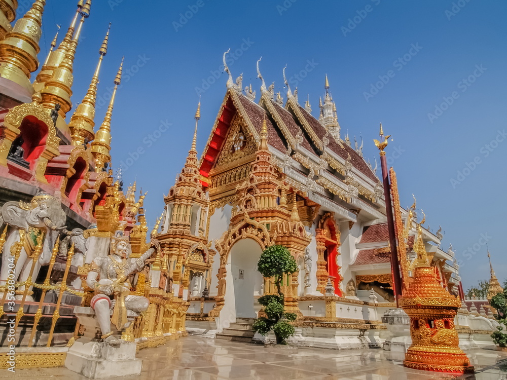 view of Buddhist temple around with many golden pagodas with blue sky background, Wat Phra That Suthon Mongkhon Khiri, Denchai District, Phrae Province, northern of Thailand.