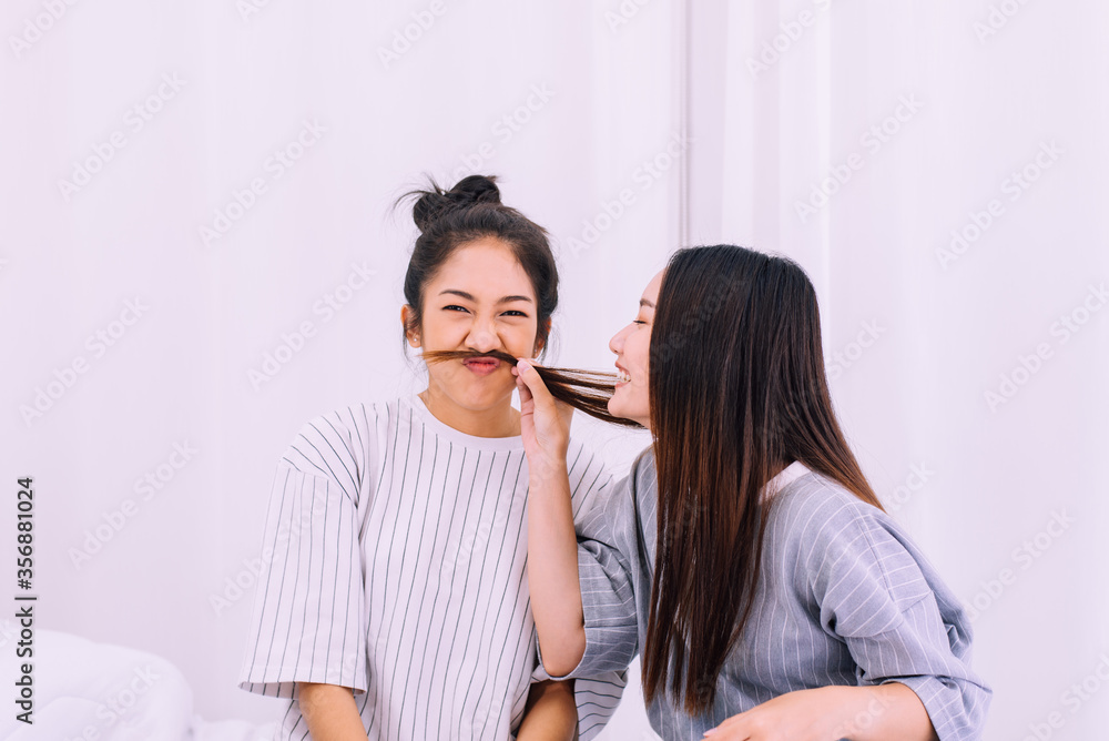 Two beautiful asian women are having fun and making fake mustaches from hair Two beautiful asian women are having fun and making fake mustaches from hair