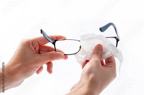 woman cleaning glasses with an alcohol-disinfecting antibacterial wipe as a prevention to kill bacteria and viruses