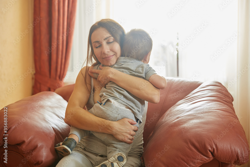 Fototapeta premium Loving mother hugging adorable baby with pleasure