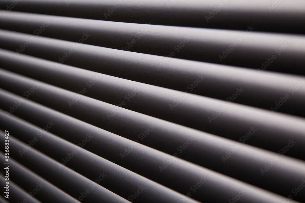 Obraz premium contrasty abstract close up filled frame background wallpaper shot of grey window blinds with rays of light shining through and leaving hard black shadows that create beautiful diagonal lines