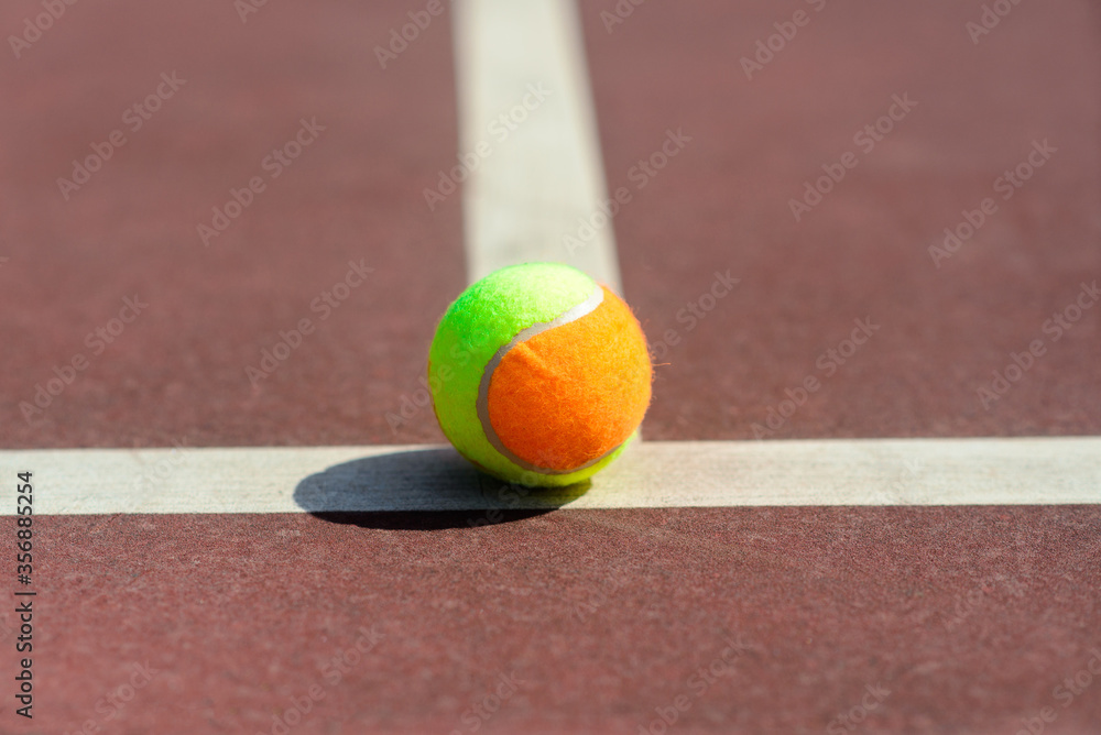 Tennis balls and rocket on court field in sunny day