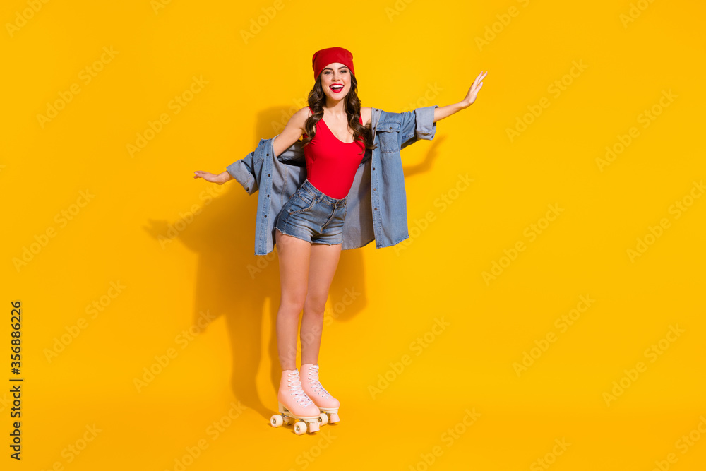 Full body photo of positive cheerful sporty youngster girl ride roller skates hold hands imagine she fly wear red headwear tank-top denim isolated over bright color background Full body photo of positive cheerful sporty youngster girl ride roller skates hold hands imagine she fly wear red headwear tank-top denim isolated over bright color background