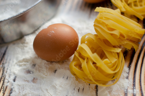 raw tagliatelle pasta with eggs on a table with flour