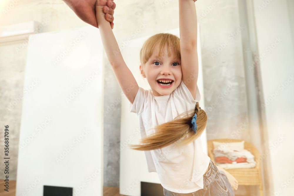 Portret of happy child is playing with parent at home. Father is spinning with daughter. Portret of happy child is playing with parent at home. Father is spinning with daughter.