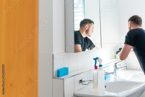 professonal cleaner cleaning a bathroom and the glass shelves in the bathroom cabinet photo