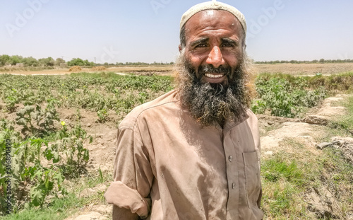 a pakistani farmer with beard working in vegetable fields and smiling 