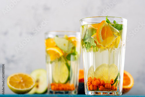 homemade lemonade with lemon, orange, sea buckthorn and mint in glasses on white background, summer drinks