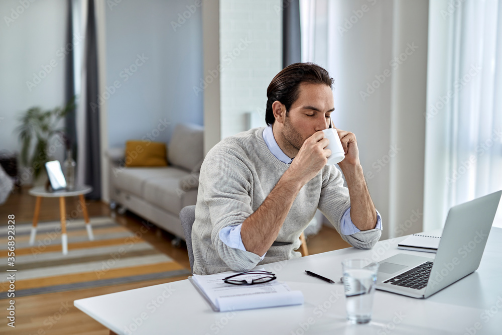 Young businessman enjoying in cup of coffee while talking on the phone at home. Young businessman enjoying in cup of coffee while talking on the phone at home.