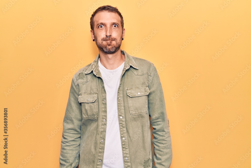 Fototapeta premium Young handsome man wearing casual clothes puffing cheeks with funny face. mouth inflated with air, crazy expression.