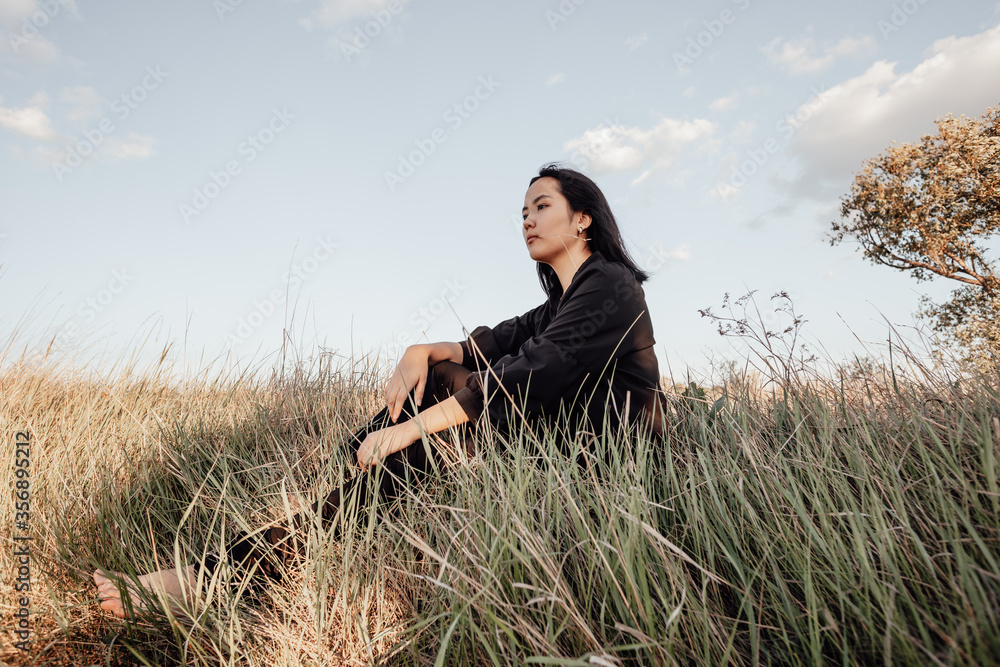 A girl is sitting in a field on the grass A girl is sitting in a field on the grass