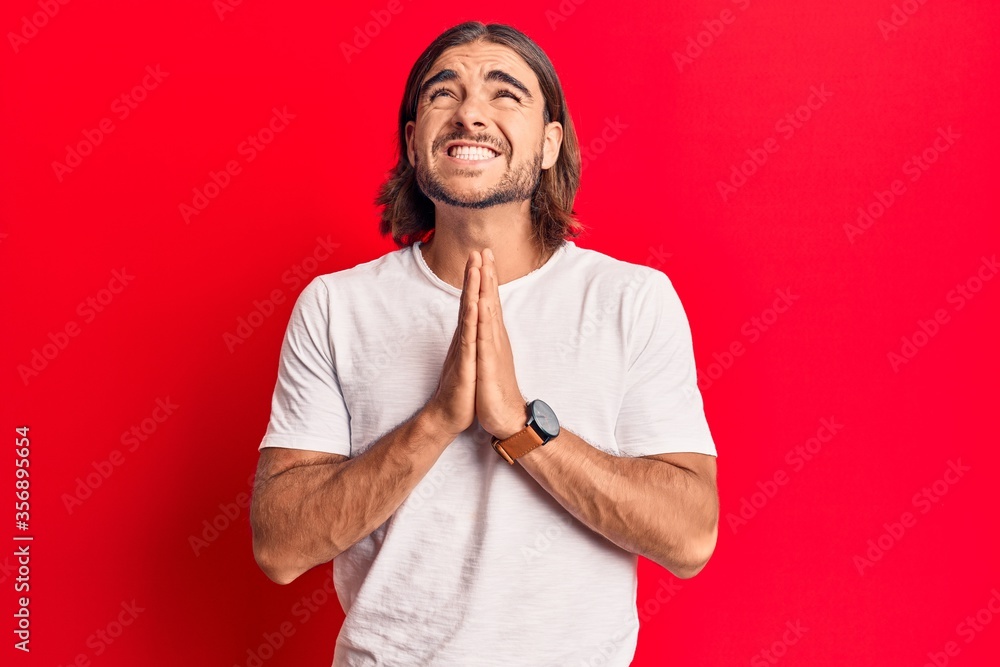 Young handsome man wearing casual clothes begging and praying with hands together with hope expression on face very emotional and worried. begging. Young handsome man wearing casual clothes begging and praying with hands together with hope expression on face very emotional and worried. begging.