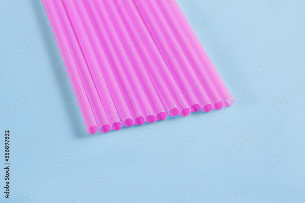 Pink plastic tubules for drinks on a blue background.- Pink plastic tubules for drinks on a blue background.-