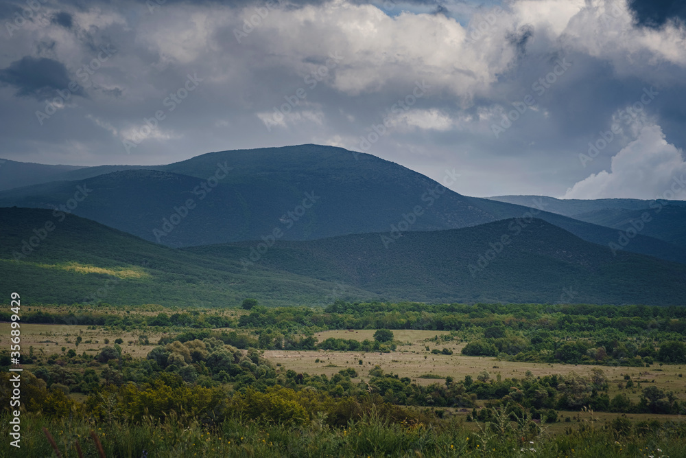 Obraz premium Picturesque green valley among the mountains before a storm.