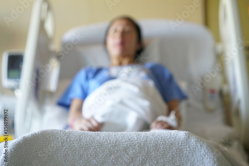 Out of focus image of Asian chinese woman patient lying in hospital ward photo