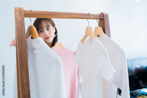 Asian woman choosing clothes dress-up closet collection mirror at home