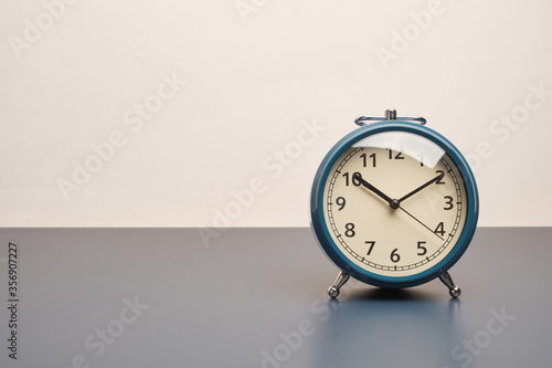 Retro alarm clock on dark blue table and white wall background with copy space.