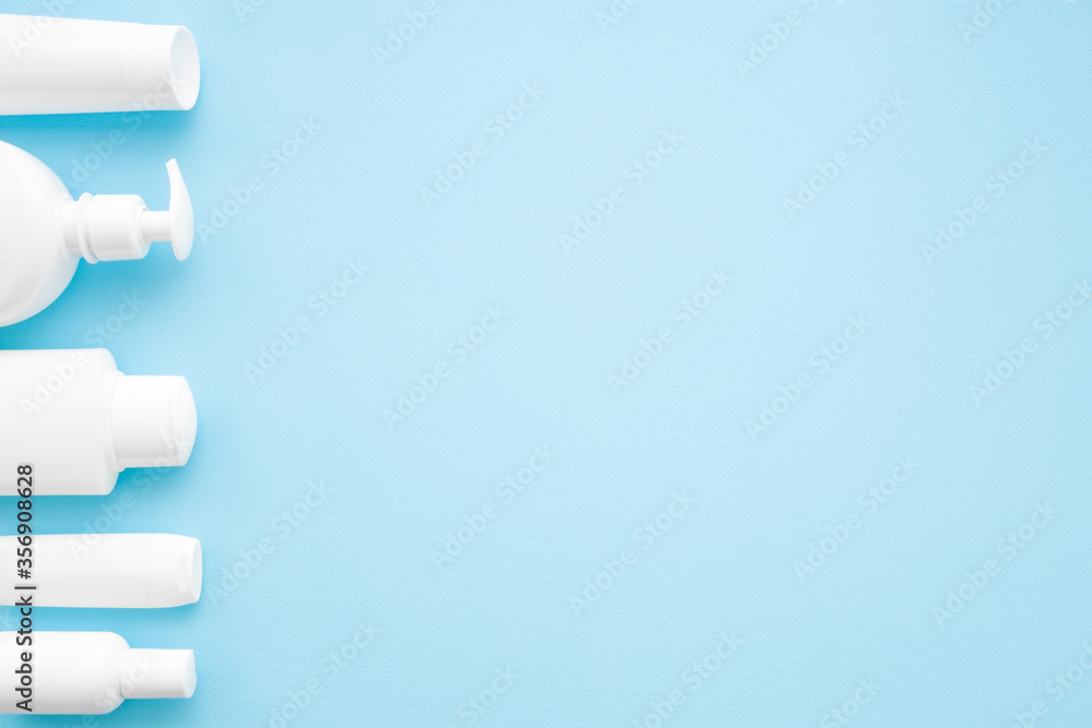 Different white toiletries on light blue table background. Pastel color. Care about face, hands, legs and body skin. Women and men beauty products. Empty place for text or logo. Flat lay. Top view. Different white toiletries on light blue table background. Pastel color. Care about face, hands, legs and body skin. Women and men beauty products. Empty place for text or logo. Flat lay. Top view.