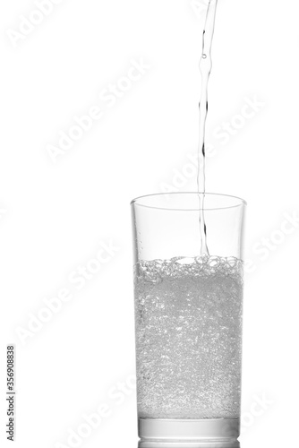 Pouring water into a glass isolated on white