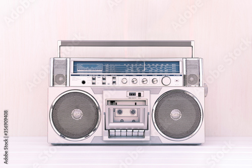 80's retro cassette radio in silver colour on light wood background. Play music concept.