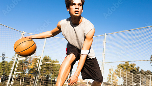 Canvas Print Fit male athlete playing basketball and dribbling the ball outdoor on a sunny summer day