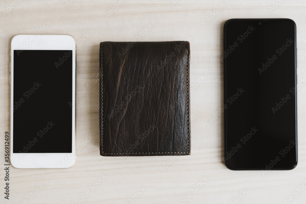 Two mobile phones and leather wallet on wooden desk, top view. Online money transfer concept Two mobile phones and leather wallet on wooden desk, top view. Online money transfer concept