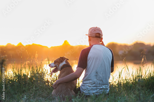 Photos Man hugs his dog in sunset by the lake