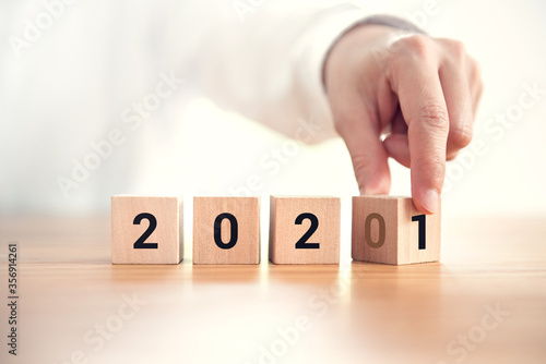 Businesswoman Hand change wood cubes New year 2020 to 2021 concept.