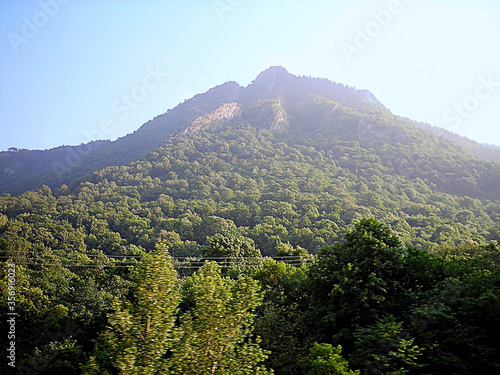 Photography A dense green forest on a mountain with a rock peak in an 4x3 format landscape photography